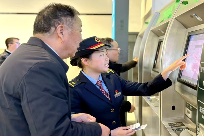 车站工作人员正在指导旅客购买车票。陈燕 摄